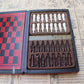 Lifestyle shot of the antique chess set placed on a coffee table beside a stack of books, emphasizing its decorative appeal.

