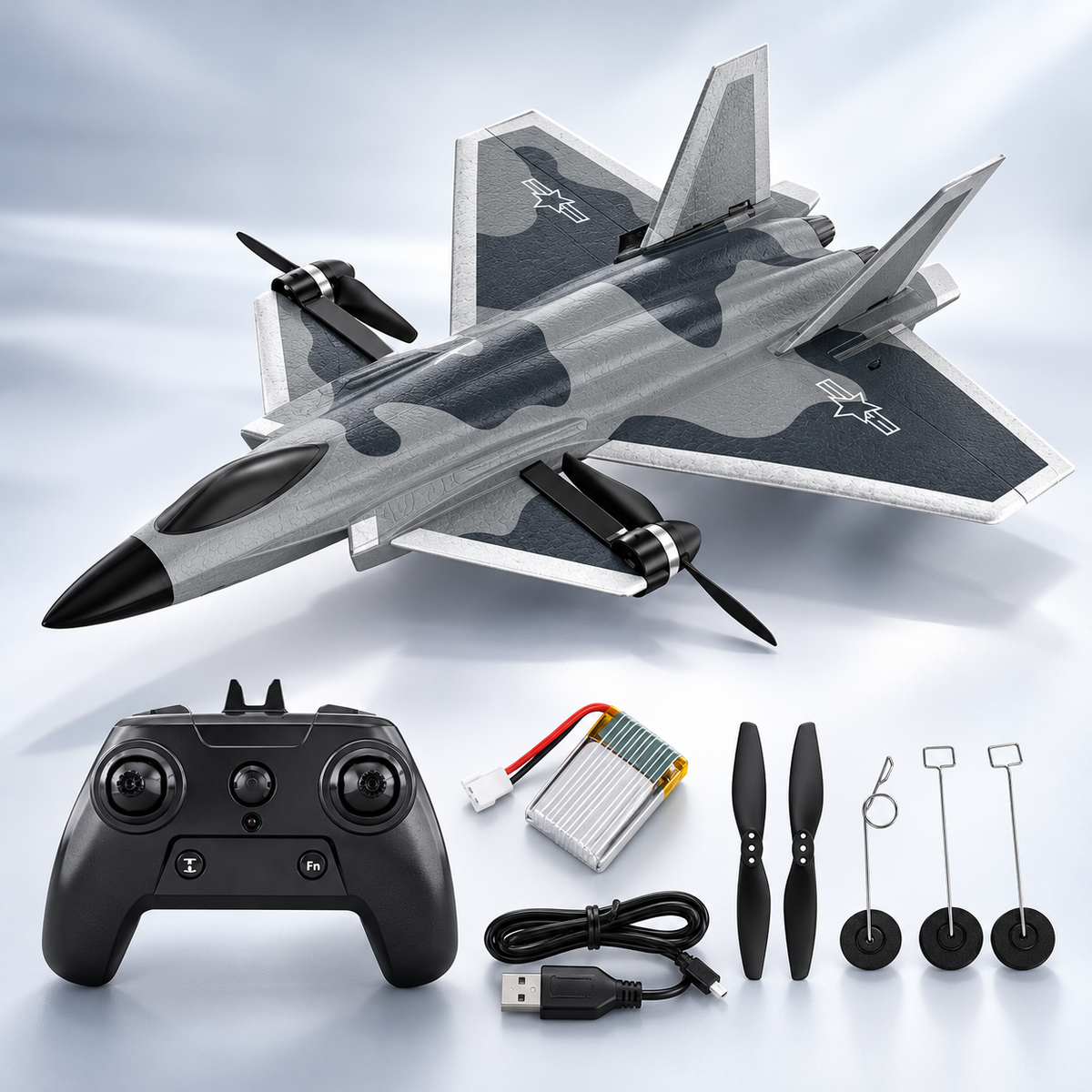 A toy remote control RC Fighter Plane with a gray and black camouflage pattern, shown with its black remote controller, battery, USB charging cable, and four black propellers on a light blue gradient background.
