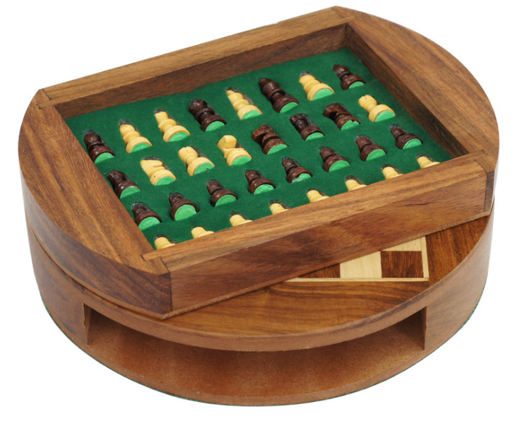 Pieces of the magnetic wooden chess set placed aboved the main playing board in their compact stoarge box