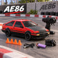 A red and black rc auto drift car set displayed on a racetrack background, including the car, black remote controller, orange traffic cones, black tires, USB charging cable, and purple battery. The AE86 logo is displayed in the top left corner.